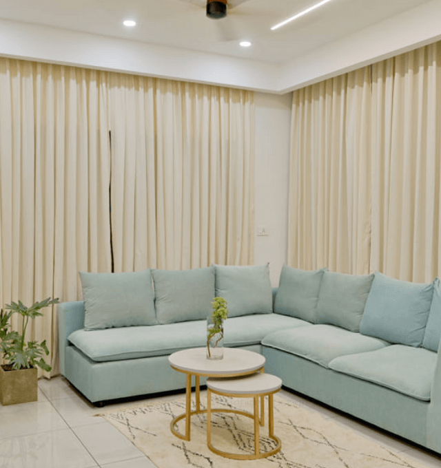 Elegant living room in a Twin Villa, showcasing a blue couch paired with a modern coffee table for a refined look.